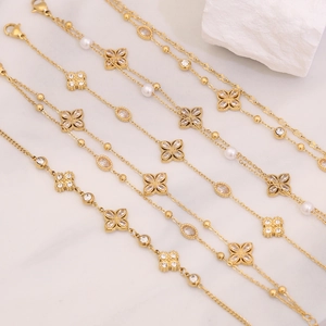 Detail of gold flower bracelets with pearls and zircons on white stone background