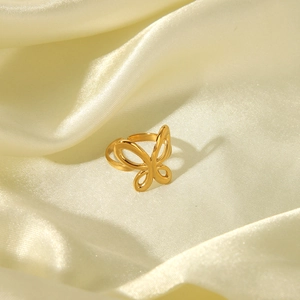 Detail of a hollow golden butterfly ring on smooth yellow satin fabric with warm lighting
