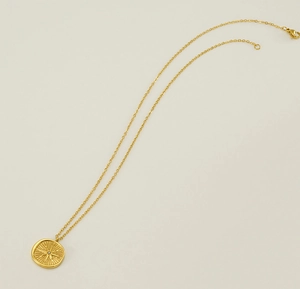 Close-up of golden starburst medallion pendant featuring a center-set sparkling diamond