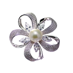 Élégante broche fleur en perle et argent avec zircons étincelants sur fond blanc
