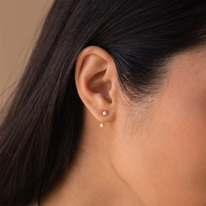 Elegant gold pearl studs featuring double white pearls shown on model for a minimalist look