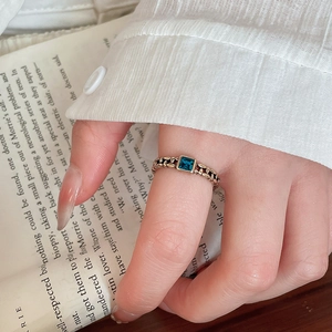 Detail of rose gold vintage chain ring with a square blue gemstone on a retro book