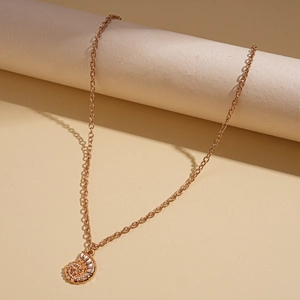Detail of golden conch pendant necklace featuring a mirror-finish and cross chain link