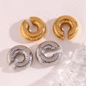 Close-up of gold and silver hammered C-shape ear cuffs featuring textured water droplet finish