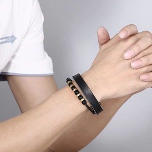 Detail of mens double-layer black leather bracelet with gold beads and steel chain