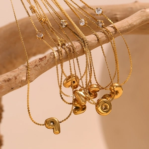Détail de pendentifs lettres dorées avec zircone sur des chaînes élégantes