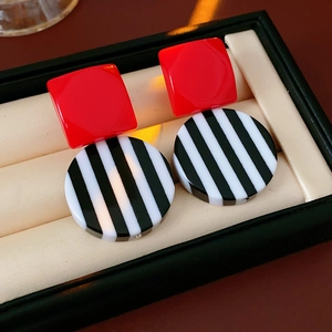 Detail view of retro geometric resin earrings with red square and black-white stripe pattern