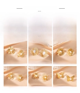 Detailed view of hollow gold flower and butterfly earrings with pearl accents