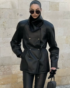 Détail du col montant et du design à double boutonnage sur la veste en similicuir