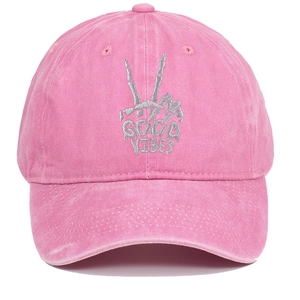 Close-up of skeleton hand embroidery and Good Vibes text on a pink washed baseball cap