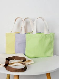 Solid color canvas tote bag in yellow, purple, green and beige on a white table