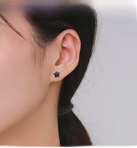 Close-up of S925 silver star stud earring with black obsidian on a female ear