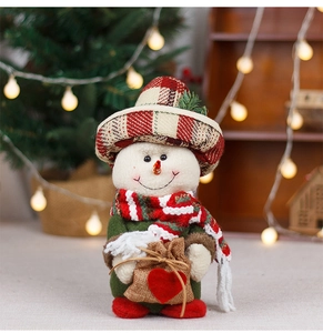 Detail of plush Christmas snowman figurine with plaid hat and red scarf in warm setting