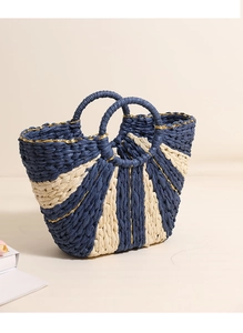 Detail of navy and beige straw tote featuring gold thread accents and round top handles