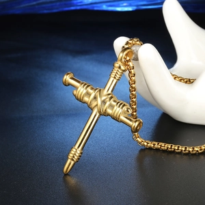 Détail macro du pendentif croix clou doré avec nœud torsadé et embouts filetés pour homme