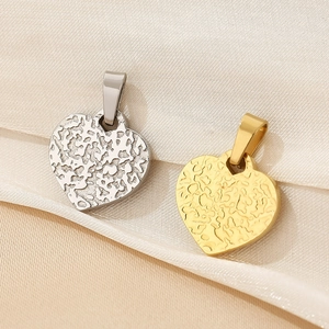 Close-up of gold and silver heart pendants with irregular hammered texture on silk