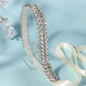 Detail of silver bridal sash featuring leaf-shaped marquise rhinestones and white ribbons