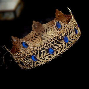 Detailed macro view of golden baroque crown featuring ornate teardrop blue gemstones