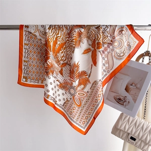 Close-up of silk printed scarf with leopard pattern and palm leaves on a metal rack