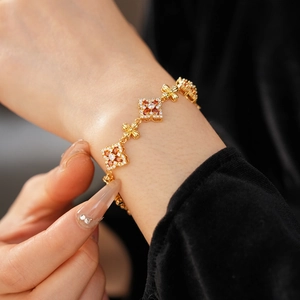Detalle de pulsera vintage de oro con flores de circón naranja y blanco en la muñeca