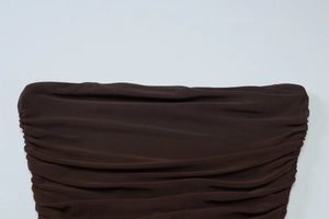 Detail of dark brown ruched fabric and sheer mesh stitching on a slim fit strapless dress