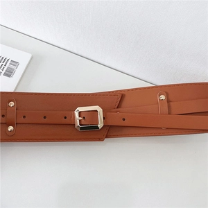 Detail of a brown leather corset belt with gold square buckle and adjustable straps