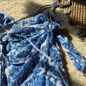 Détail d'un sarong paisley bleu et blanc avec texture en maille et bordure en dentelle