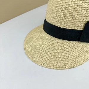 Close-up of the woven straw texture and elegant black silk bow on the equestrian hat