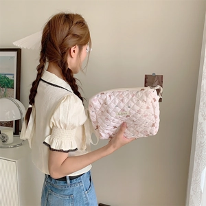 Mannequin tenant une trousse de maquillage rose matelassée avec motifs lune et étoiles