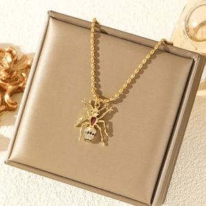 Golden spider pendant necklace featuring a red teardrop gemstone on a gold jewelry box