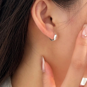 Macro shot of minimalist 925 sterling silver hoop earrings on a female model