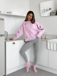 Close-up of pink crewneck sweater featuring detailed red and white dachshund embroidery
