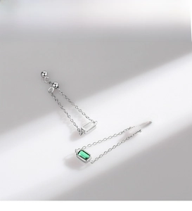 Detail of silver long chain earrings with emerald-cut green cubic zirconia stones