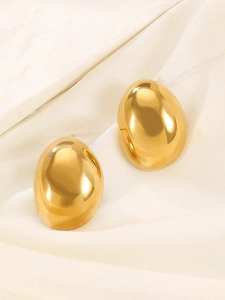 Close-up of elegant gold oval stud earrings with a polished mirror finish on silk