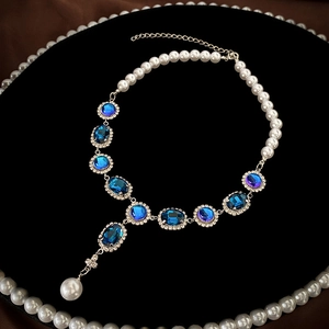 Vintage Y-shaped pearl necklace with oval blue gemstones and silver tassel on velvet