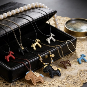 Détail de colliers pendentif cheval avec cuir et plaquage or dans un écrin à bijoux