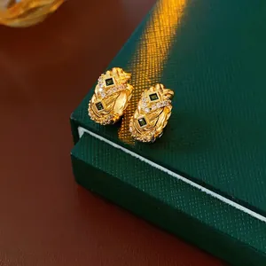 Vintage gold hoop earrings with emerald green stones and zircon accents on velvet box