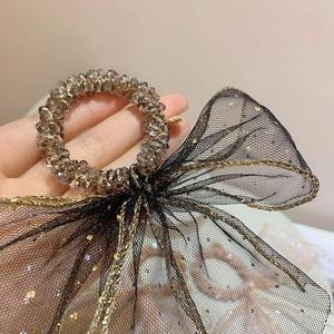 Detail of beaded hair tie featuring black mesh bow with gold glitter and brown beads