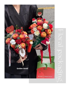 Close-up of Christmas flower box featuring red roses, apples and festive pine decorations