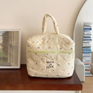 Close-up of quilted yellow checkered makeup bag with cherry print and top handle