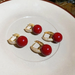 Macro detail of red zircon resin hoop earrings with gold finish and sparkling accents
