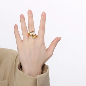 Detail of minimalist double-pearl open ring in gold finish on a model hand