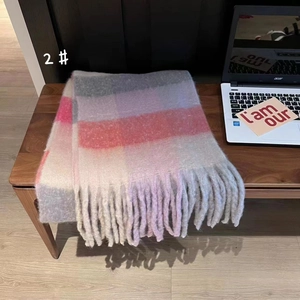 Close-up detail of soft plaid scarf with thick tassels on a wooden table surface