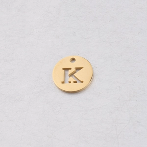 Vue macro d'un pendentif rond 12mm en acier doré avec gravure de la lettre K évidée