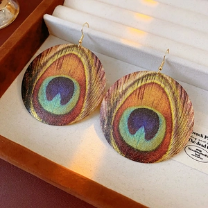 Close-up of bohemian round peacock feather earrings in a premium jewelry display box