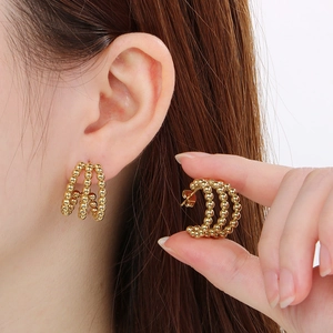 Detail view of stylish gold stainless steel triple-row beaded hoop earrings on model