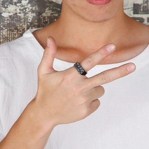 Detailed close-up of a men's black stainless steel ring with a grey geometric texture