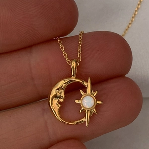 Goldene Halskette mit Halbmond und Stern Anhänger, weißer Opal-Schmuck in der Hand