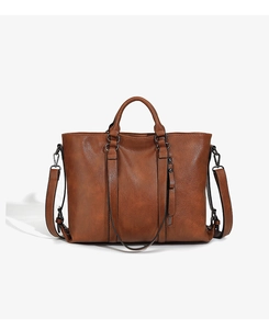 Close-up of brown soft leather tote bag showing vertical zipper detail and shoulder strap