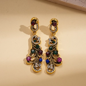 Détail de boucles d'oreilles vintage dorées avec cristaux colorés et travail de filigrane